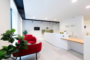 A modern reception area with a counter, seating, and a wall-mounted clock. - Yugo Lee Point (Cork)