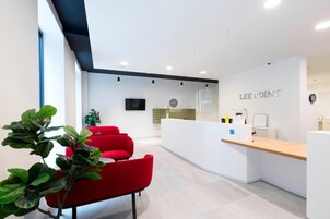 Una moderna zona de recepción con mostrador, asientos y un reloj en la pared.