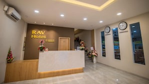 A hotel reception area with a reception desk, a clock, and a wall-mounted clock. - RAV Hotel (Tanjung Pinang)
