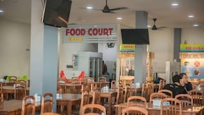 A food court with multiple tables and chairs, a sign for 'Food Court', and a counter with a person behind it. - RAV Hotel (Tanjung Pinang)