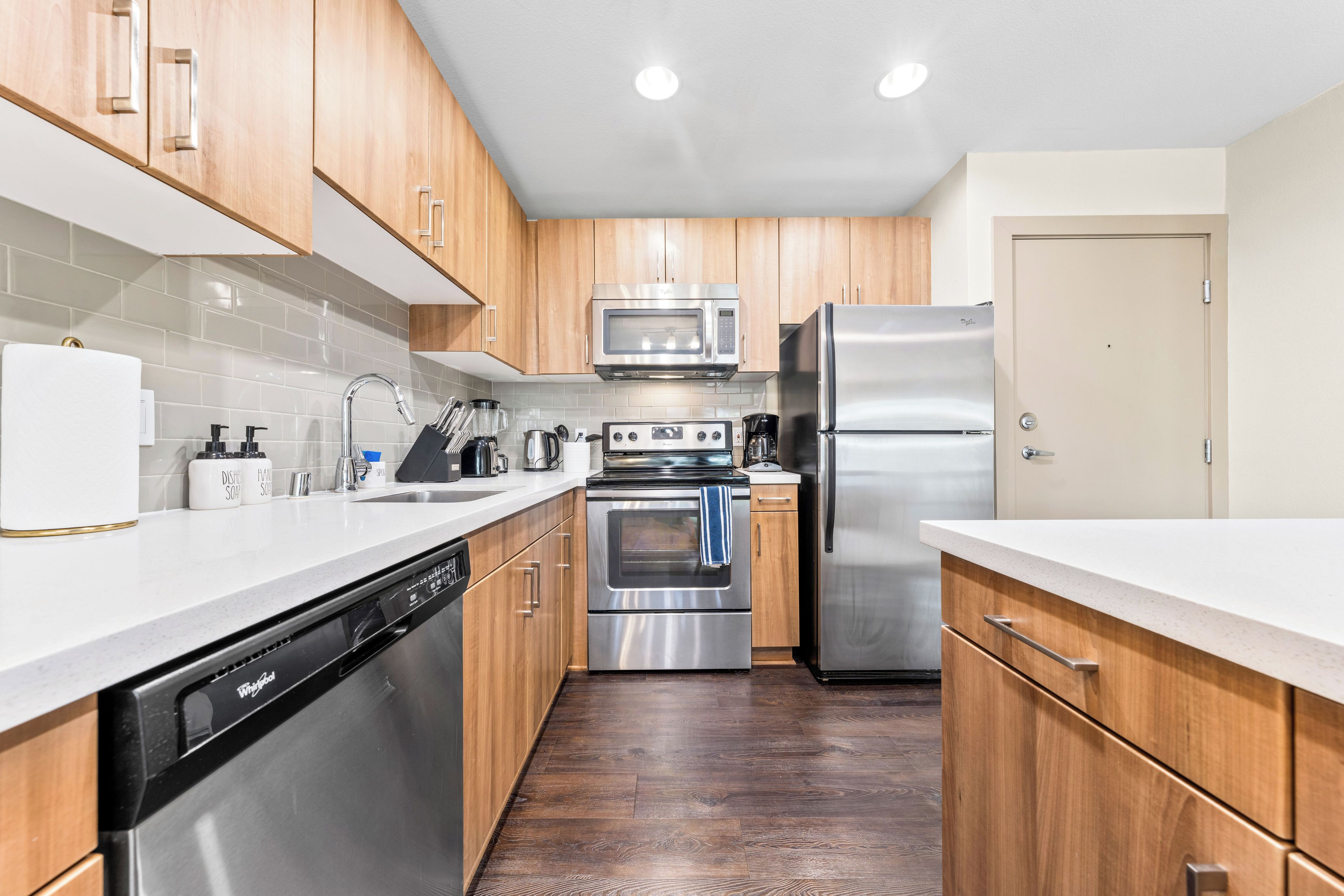A modern kitchen with wooden cabinets, stainless steel appliances, and a dishwasher.