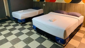 Two single beds with mattresses on blue frames, a checkered floor, and a colorful abstract wall. - Holiday Hotel Pekanbaru (Pekanbaru)