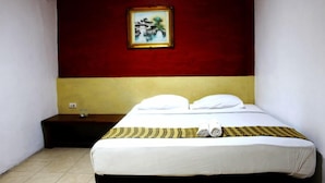 A hotel room with a bed, a nightstand, a painting on the wall, and a window. - Holiday Hotel Pekanbaru (Pekanbaru)