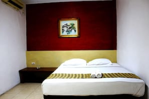 Een hotelkamer met een bed, nachtkastje, schilderij aan de muur en een raam.