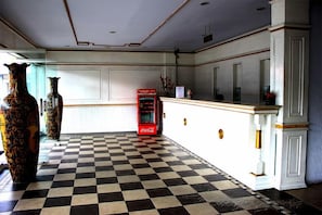 Een geruit vloerkleed, een Coca-Cola automaat en twee grote vazen.