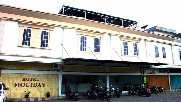 A building with a sign reading 'HOTEL HOLIDAY' and a row of parked motorcycles in front. - Holiday Hotel Pekanbaru (Pekanbaru)