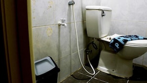 A bathroom with a toilet, a shower, and a trash bin. - Holiday Hotel Pekanbaru (Pekanbaru)