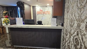 A hotel reception desk with a modern design, a sign reading 'ENRICH HOTEL', and a decorative wall with a floral pattern. - Enrich Hotel Semenyih (Semenyih)