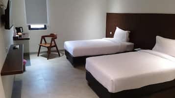 A hotel room with two beds, a desk, a chair, and a television.