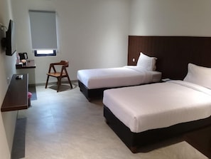 A hotel room with two beds, a desk, a chair, and a television. - Bell Hotel Merauke (Merauke)