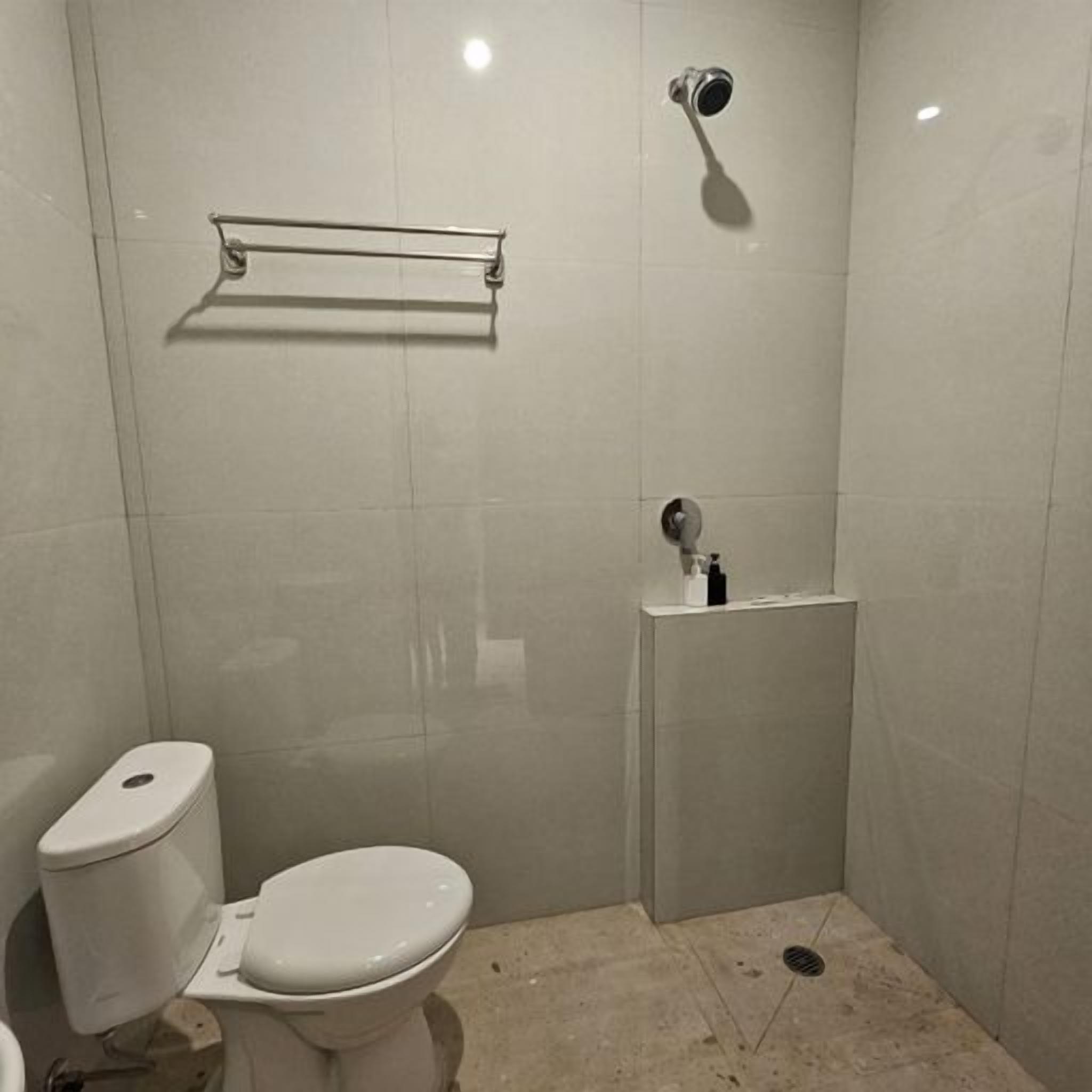 A small, enclosed bathroom with a toilet, a shower, and a sink.