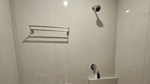 A small, enclosed bathroom with a toilet, a shower, and a sink. - Bell Hotel Merauke (Merauke)