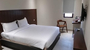 A hotel room with a single bed, a small desk, a chair, a TV, and a window. - Bell Hotel Merauke (Merauke)