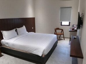 A hotel room with a single bed, a small desk, a chair, a TV, and a window. - Bell Hotel Merauke (Merauke)