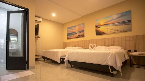 A hotel room with two beds, a bathroom, and a view of the beach. - SH Hotel (Pangandaran)