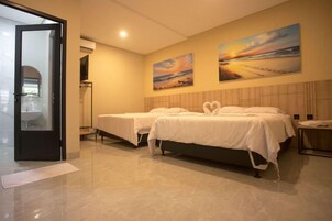 Habitación de hotel con dos camas, baño y vista a la playa.