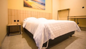 A hotel room with a bed, a bench, a painting on the wall, and a mirror. - SH Hotel (Pangandaran)