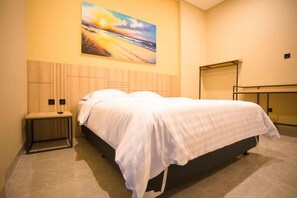 A hotel room with a bed, a bench, a painting on the wall, and a mirror. - SH Hotel (Pangandaran)