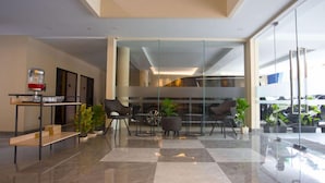 A modern lobby with a checkered floor, glass partitions, and seating areas. - SH Hotel (Pangandaran)