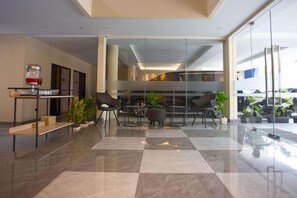 A modern lobby with a checkered floor, glass partitions, and seating areas. - SH Hotel (Pangandaran)