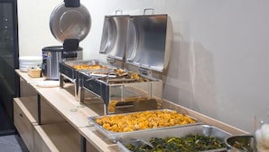 A buffet setup with various food items and a coffee machine. - SH Hotel (Pangandaran)
