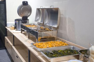 Montaje de bufé con diferentes platillos y una máquina de café.