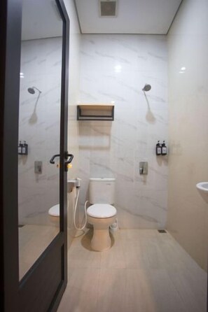 A modern bathroom with a toilet, bidet, and a mirror. - SH Hotel (Pangandaran)
