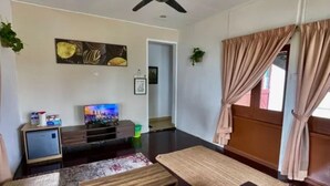 A living room with a flat-screen TV, a ceiling fan, and a large window with curtains. - Lilla Sea View Retreat, Malacca (Alor Gajah)