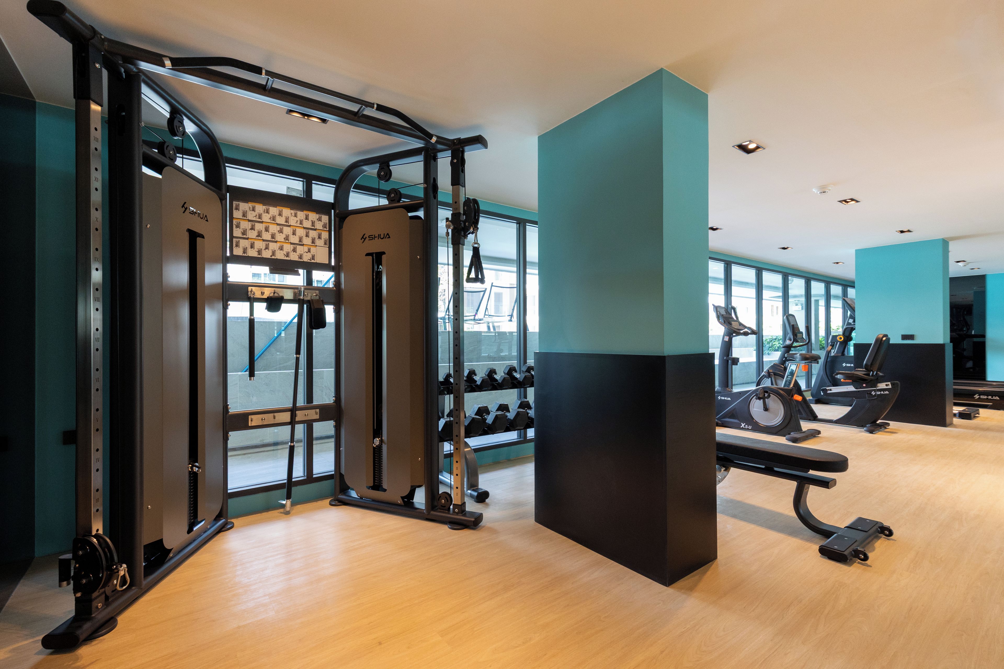 A gym with exercise equipment, weight racks, and a bench.