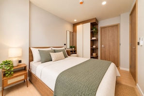 Quarto com cama, mesa de cabeceira, abajur e uma planta.