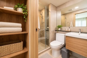 Un bany modern amb una dutxa de vidre, un vàter i un lavabo amb mirall.