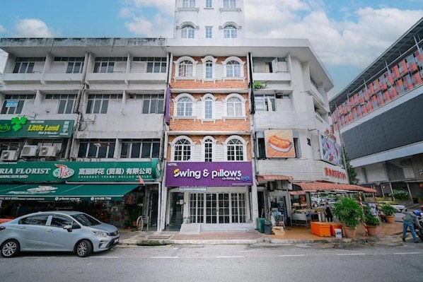 Un hotel con fachada tradicional, múltiples ventanas y un letrero que dice 'Swing & Pillows'.