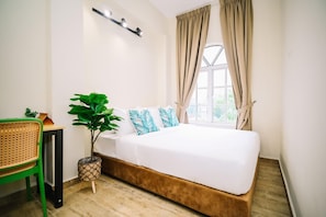 Un dormitorio con cama, planta en maceta, silla y ventana con cortinas.