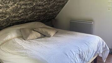 Une chambre à coucher avec un lit, un radiateur et un mur orné d’un motif floral.