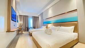A hotel room with two beds, a desk, and a TV. - Cocotree Resort (Panglao)