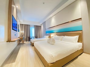 Habitación de hotel con dos camas, un escritorio y un televisor.
