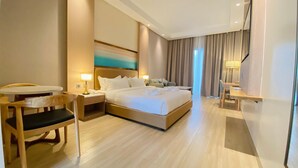 A hotel room with a large bed, bedside tables, a desk, and a chair. - Cocotree Resort (Panglao)
