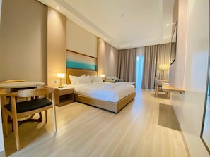 Una habitación de hotel con una cama grande, mesitas de noche, un escritorio y una silla.