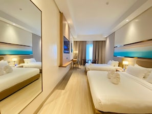 A hotel room with two beds, a TV, a desk, and a view of the outdoors. - Cocotree Resort (Panglao)