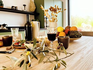 A table with a bottle, glasses, olives, and a bowl of fruit. - Art-filled farmhouse in the Valle d'Itria trulli (Locorotondo)