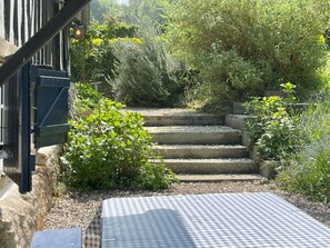 A checkered outdoor seating area with steps leading to a stone wall. - Holiday Home 'Le Paradis' with Private Terrace, Private Garden and Wi-Fi (Les Champeaux)