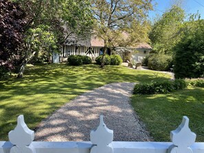 Ein Weg führt zu einem Haus mit Garten, Rasen und Zaun.