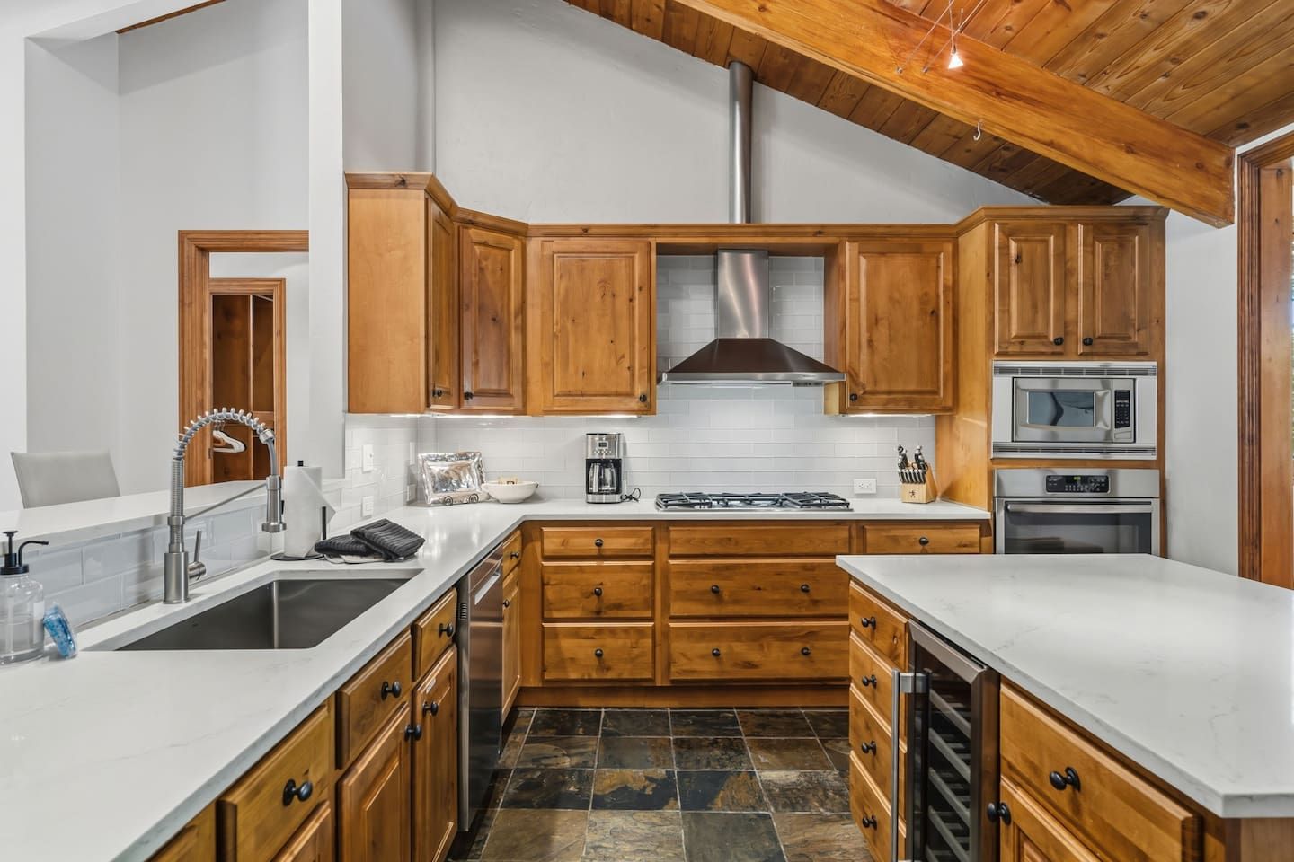 Una cocina con armarios de madera, una campana extractora de acero inoxidable, un microondas y un horno.