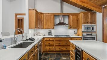 Una cocina con armarios de madera, una campana extractora de acero inoxidable, un microondas y un horno.