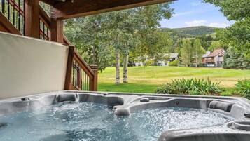 Un jacuzzi con terraza de madera y vista a un paisaje verde.