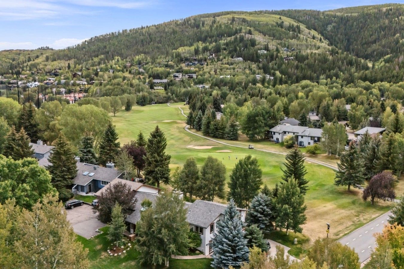 Un quartier résidentiel avec des maisons, un terrain de golf et un paysage vallonné.