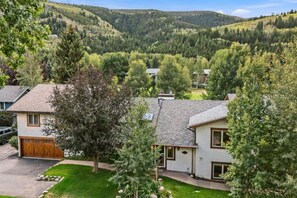 Un barrio residencial con casas, un árbol y un paisaje montañoso al fondo.