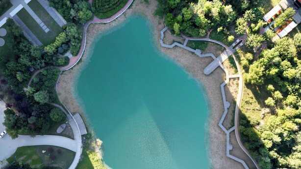 An aerial view of a park with a large pond, pathways, and surrounding greenery. - Steigenberger Harbin Sunac Land (Harbin)