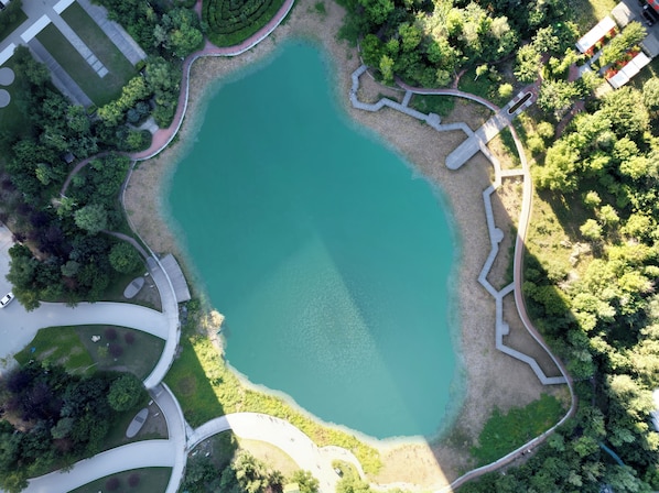 An aerial view of a park with a large pond, pathways, and surrounding greenery. - Steigenberger Harbin Sunac Land (Harbin)