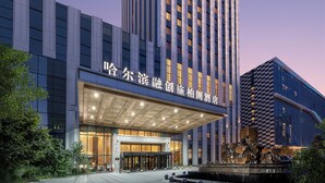 A high-rise hotel with a prominent entrance and a large, illuminated sign. - Steigenberger Harbin Sunac Land (Harbin)